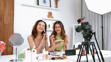 Etkilenen iki ortak canlı yayın yapan video görüntülerini sosyal medya ya da blog üzerinden gözden geçirir. Canlı kozmetik stüdyosu ışıklandırması olan mutlu genç bir kız pazarlama için internet üzerinden yayın yapıyor..