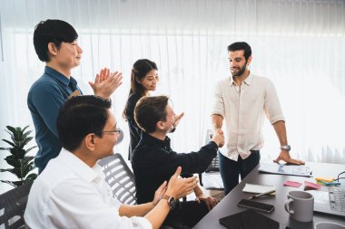 Çeşitli ofis çalışanları stratejik iş pazarlama toplantısı üzerine anlaşma yaptıktan sonra el sıkışıyor. Takım çalışması ve olumlu tutum verimli ve destekleyici bir iş yeri yaratır. Tedbirli