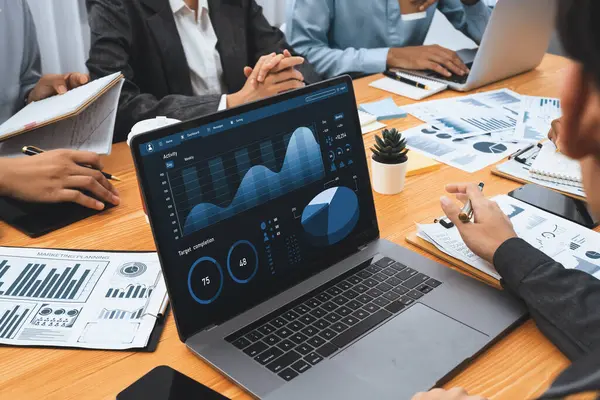 Çok ırklı analist ekibi toplantı masasındaki finansal verileri analiz etmek için BI Fintech yazılımı kullanıyor. Finansal konsol veri ekranında pazarlama göstergesi için analiz edilmiş grafikle birlikte. Uyum