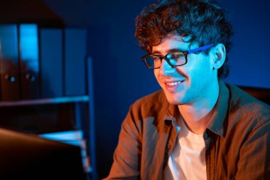 Neon Light Modern Ofis 'te yaratıcı bir başlangıç projesi için bilgisayara odaklanan gülümseyen genç iş adamı. Düşünüyorum da, pazarlama ağı yaratıcıdan pazar kanalı tasarım konseptine çevrimiçi planlama. Toplayıcı.