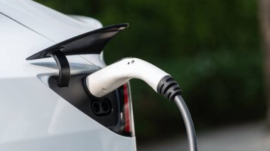 Elektrikli araç portuna bağlı EV şarj prizi kolu şarj istasyonundan şarj oluyor. Modern tasarlanmış EV araba ve daha iyi bir gelecek konsepti için temiz enerji sürdürülebilirliği. Eşzamanlama