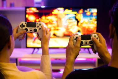 Ellere odaklan ya da televizyondaki neşeli oyuncu video oyununa. Bulanık ekran ile joystick 'i yan yana kullan. Stüdyo odasındaki rahat evdeki neon ışıklı masada atıştırmalık ve içecekler. Varsayım.
