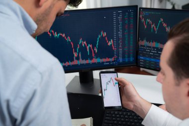 Akıllı telefon üzerinden dijital para birimini tartışan borsa simsarları iki ekranlı gerçek zamanlı çevrimiçi dinamik verilere odaklanarak, modern işyerindeki olası trend yatırımlarını analiz ediyorlar. Satılabilir.