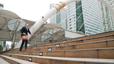 Kafkasyalı zeki işadamı şehir manzarası ile çevrili merdivenleri çıkıyor. Hırslı proje yöneticisinin modern inşaatta zorlu bir iş ya da yatırım fırsatı bulması. Urbane.