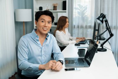 Modern ofiste poz vermek için elinde kahve fincanı tutarken kameraya bakan zeki Asyalı işadamı profili. Bulanık arkaplan bayan meslektaşı e-posta pazarlama raporunu kontrol etmek ya da cevap vermek için bilgisayar üzerinde çalışıyor. İnfobahn.