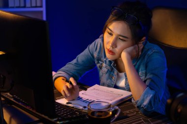 Bitkin düşmüş, genç, güzel Asyalı yaratıcı hisler, bilgisayardan e-posta beklemek için bekliyor. Projenin yaratıcısı sosyal medyanın veri tablosunu gece vakti neon ofiste karşılaştırıyoruz. Taktik.