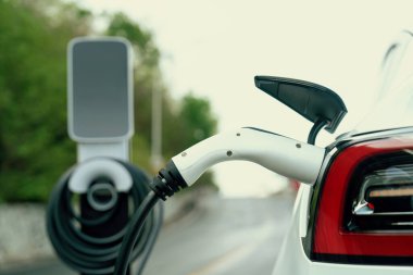 Kapalı EV şarj kolu fişe takıldı veya elektrikli arabaya bağlandı, EV araba aküsünü temiz çevre için sıfır CO2 emisyonu ile alternatif ve sürdürülebilir enerjiyle şarj etti. Kalıcı