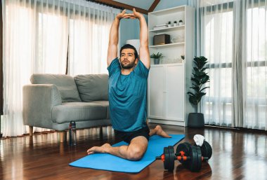 Atletik ve sporcu adam, evdeki fiziğe ve sağlıklı spor yaşam tarzına uygun vücut egzersizlerinden önce ısınıyor ve esniyor. Gaiety ev egzersizi antrenman konsepti.
