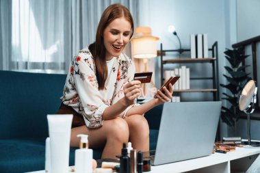 Genç mutlu kadın internetten alışveriş yaparak ürün satın alırken aynı zamanda internet üzerinden online ödeme sistemi ile çevrimiçi mağaza platformundan en yüksek siber güvenlik tarafından korunan ürünler sipariş ediyor.