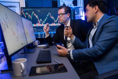 İki borsa simsarı gece monitörde döviz kurunda dinamik yatırım grafiğini tartışıyor. İş adamı ortakları iş yerindeki neon ışığı altında yüksek borsada kahve toplantısı yapıyor. Satılabilir.