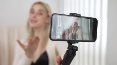 Genç sosyal medyum kadın selfie çubuğuyla moda videosu yapıyor. Blogcu kameraya gülümserken çevrimiçi kıyafetleri izleyicilere ya da takipçilere vlog sattırıyor. Blithe