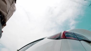 Dipte yavaş çekimde çalışan adam elektrik şebekesine bağlı EV araba aküsünü şarj ediyor. Elektrik endüstrisi çevre dostu araç için elektrik endüstrisi olarak çalışıyor. Yararlı