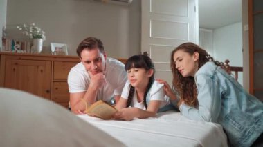 Çocukluk hikayeleri anlatan uyku zamanı, anne ve baba rahat ve rahat yatak odasındaki küçük kızlarına birlikte fantezi kitabı okuyorlar. Modern aile eğlencesi. Titiz