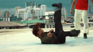 Profesyonel Asyalı sokak dansçısı çatıda çok kültürlü arkadaşlar dans ederken B boy dansı yapıyor. Genç modern dans grubu hip hop hareketi yapıyor. Tarz, moda, aksiyon. Açık hava sporu 2024 hiphop..