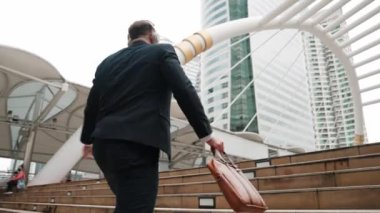 Kafkasyalı zeki işadamı şehir manzarası ile çevrili merdivenleri çıkıyor. Mutlu hırslı proje yöneticisinin arka planı kulaklıktan rahatlatıcı müzik dinlemek ve merdivenleri çıkarken şarkıya geçmek. Urbane.