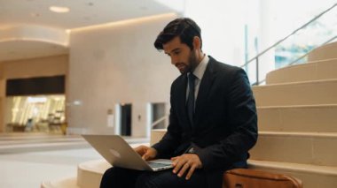 Merdivenlerde dizüstü bilgisayar kullanarak çalışan ya da plan yapan yetenekli bir yatırımcı. İş adamı çalışırken ve merdivenlerde otururken takım elbise giyer. Akıllı yönetici işini bitirip başka bir yere gidiyor. Sevinçli..