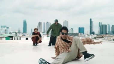 Profesyonel break dans takımı çatıda çok kültürlü arkadaşlar varken break dans alıştırması yapıyor. Genç modern dans grubu hip hop hareketi yapıyor. Tarz, moda, aksiyon. Açık hava sporu 2024 hiphop..
