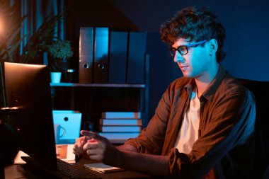 Genç işadamı, Neon Light Modern Ofis 'te yaratıcı bir başlangıç projesi için bilgisayara odaklanıyor. Düşünüyorum da, pazarlama ağı yaratıcıdan pazar kanalı tasarım konseptine çevrimiçi planlama. Toplayıcı.