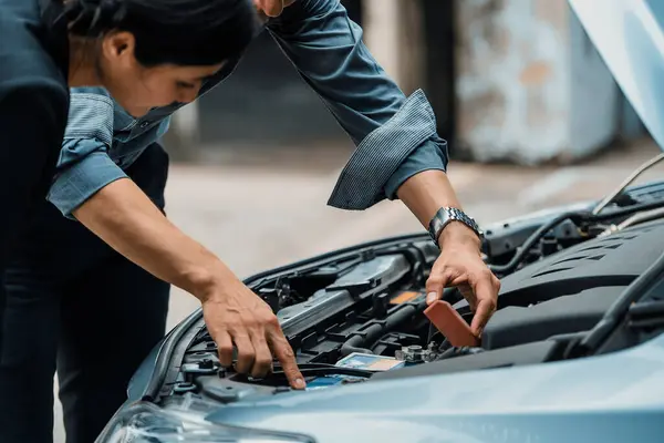 Man help woman fix the car problem. He pop up the car hood to repair the damaged part. uds