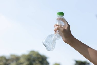 Geri dönüşümlü plastik şişe gökyüzü arka planında el ele tutulur. Geri dönüşüm için plastik atık bulundurmak etkili geri dönüşüm yönetimi ile temiz çevreyi desteklemek için konsepti azaltmak ve yeniden kullanmak. Döngü