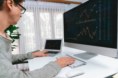 Bilgisayar ve dizüstü bilgisayarı kullanarak, çalışma masasındaki dinamik artırılmış borsa grafiğinin en yüksek kar değerini araştıran bir tüccar, modern ofisteki ekrandaki döviz kuru değerini analiz ediyor. Bireysel.
