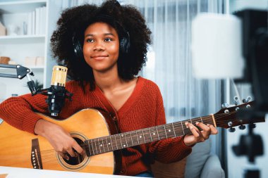 Güzel Afrikalı Kadın Etkilenen 'in sunucu kanalı akıllı telefondaki yayın stüdyosunda gitar çalarak şarkı söylüyor. Canlı sosyal medyada müzik blogcusu zamanı. Ses yaratıcısı kavramı. Tatlandırıcı.