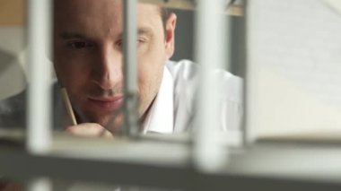 Kafkasyalı mimar mühendisinin yakın çekimi ev inşaatını denetlemek ve bina malzemelerini kontrol etmek. Proje yöneticisi modele dikkatlice bakarken kalemi işaret ediyor. Yönlendirici.