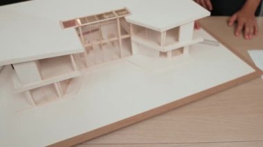 Mimari ekipman kullanarak yavaş çekim ev tasarımcısı bir plan çizerken, iç mimari tasarımcı da müşterilerin talebine göre renk örneklerinden uygun renkler seçiyor. Değiştirilmiş