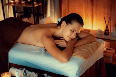 Beyaz kadın müşteri stres önleyici spa masajının keyfini çıkarıyor ve lüks otel ya da otelde sıcak mum ışığında güzellik teniyle eğleniyor. Sessiz.
