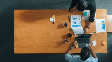 Bilgi analiz belgeleriyle toplantı masasında otururken yatırımcılarla finansal grafik hakkında konuşan yetenekli proje yöneticisinin üst görüşü. Çeşitli takımlar tartışır ve beyin fırtınası yapar. Cemaat.