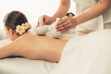 Sıcak bitkisel top spa masaj vücut tedavisi, masör nazikçe bitki torbasını çift müşteri vücuduna bastırıyor. Aromaterapi dinlenme sükuneti ve sükuneti kaplıca salonundaki atmosferi aydınlatıyor. Sessiz.