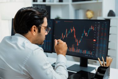 Akıllı tüccar işadamı, modern merkez ofisindeki araştırma pazarında en yüksek kârlı finansal teknolojiye yatırım yaparak bilgisayar üzerinde iki dinamik borsa yatırım ekranını analiz ediyor. Tahmin et..
