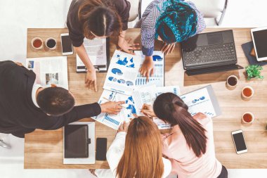 Modern ofisteki iş adamları ve iş kadınlarıyla grup toplantısındaki iş adamlarının en üst düzey görüşü, masada dizüstü bilgisayar, kahve ve belge ile. Kurumsal şirketler uds