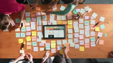 Ux Ui tasarımı kullanılarak dijital program ve yazıları tartışan ve gösteren geliştirici ekibin hava görüntüsü. İş dünyasına tepeden bakan insanlar telefon ve bilgisayar için kablo prototipi geliştiriyorlar. Sempozyum.