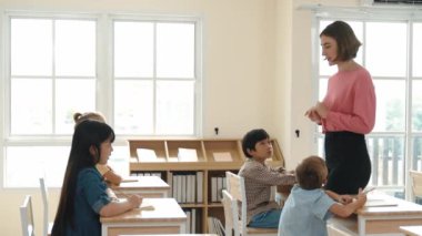 Kafkas asıllı zeki öğrenci sınıf çalışmalarını açıklayan öğretmen. Çocuklar okulda öğrenirken ya da ders çalışırken genç öğretmen tahtada durup dersten bahsediyor. Eğitim. Pedagoji.