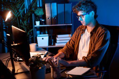 Genç işadamı, Neon Light Modern Ofis 'te yaratıcı bir başlangıç projesi için bilgisayara odaklanıyor. Düşünüyorum da, pazarlama ağı yaratıcıdan pazar kanalı tasarım konseptine çevrimiçi planlama. Toplayıcı.