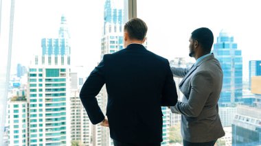 Arkaya bakan iddialı iş adamlarından oluşan farklı bir ekip süslü ofiste dikilip şehir manzarası siluetine bakıyorlar. Kararlılık ve iş hırsları kariyerlerini parlak bir geleceğe taşır.