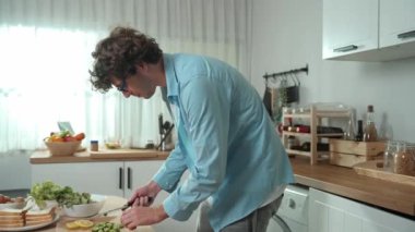 Mutlu baba yemek pişirirken müziğe geçiyor ve modern mutfakta öğle yemeği hazırlıyor. Aktif baba, sebze ve mutfak gereçleri ile çevrili sağlıklı yemek ya da salata yaparken şarkıyla dans ediyor. Pedagoji.