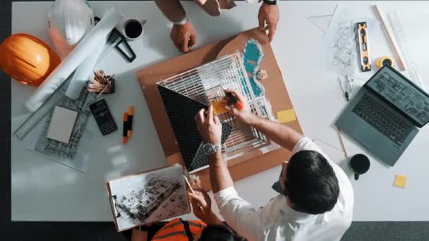 アーキテクトエンジニアチームの最上層ビューは ラップトップ セーフティヘルメット プロジェクト計画のテーブルで建物の建設を設計するために協力しながら 家のモデルに粘着性のあるノートを貼ります アライメント — ストック動画