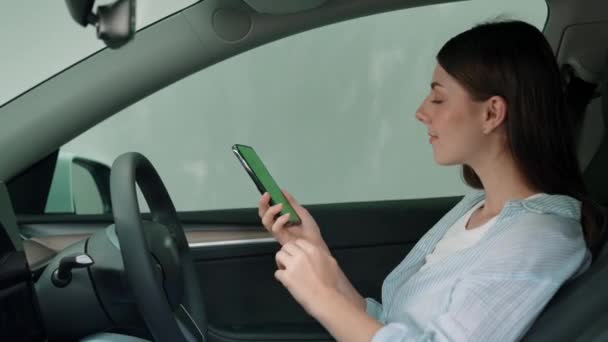 度假公路旅行与环保汽车的概念 环保意识很强的年轻夫妇坐在驾驶座上 手持空白复制空间的绿色荧幕车显示器 以检测电动车的电池状态 高级备选案文 — 图库视频影像