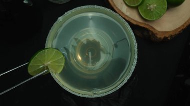 Macrography, a top-down view of a refreshing margarita is presented in a glass adorned with a green lime slice, all set with black background. Each close-up shot of the cocktail and lime. Comestible. clipart