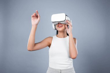 Gri arka planı olan zeki bir kadın metaevrene bağlı VR kulaklık takıyor, gelecekçi siber uzay topluluğu teknolojisi. Zarif bir kadın sanal bir manzara gördüğü için heyecanlı. Halüsinasyon.