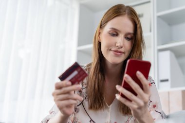 Genç mutlu kadın internetten alışveriş yaparak ürün satın alırken aynı zamanda internet üzerinden online ödeme sistemi ile çevrimiçi mağaza platformundan en yüksek siber güvenlik tarafından korunan ürünler sipariş ediyor.