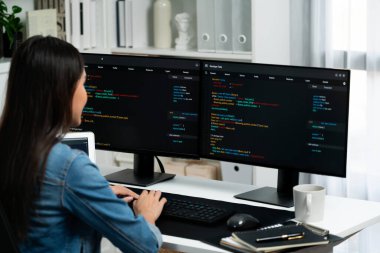 İnternet sitesi uygulamasının kodlama verileriyle birlikte online bilgi yazarak kot gömlek giyen genç Asyalı geliştirici. Güvenlik analizi ile çevrili iki ekran. Taktik.