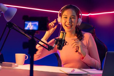 Yaratıcı yayın kanalı sosyal medyada pozitif podcasttaki dinleyicilerle birlikte müziği dinliyor, pastel renkli kulaklıklar takıyor, neon stüdyodaki kameraların mikrofon kayıtlarını kullanıyor. Taktik.