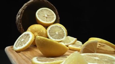 Limon dilimleri titizlikle koyu siyah bir yüzey üzerinde kırsal bir sepetin arka planına dizilmiştir. Her dilim, yumuşak ışıkla kaplanmış arka planda, Makrografi. Geliştirilebilir.