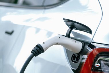 Elektrikli araç portuna bağlı EV şarj prizi kolu şarj istasyonundan şarj oluyor. Modern tasarlanmış EV araba ve daha iyi bir gelecek konsepti için temiz enerji sürdürülebilirliği. Eşzamanlama