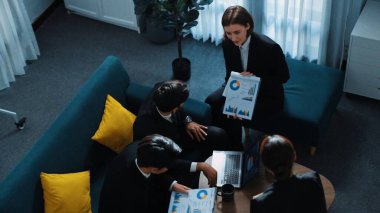 Üst düzey proje yöneticisi yatırım grafiğini iş adamlarına sunarken, kadın yatırımcı da toplantıya katılıyor. Çeşitli iş adamları toplantı odasında pazarlama stratejisi planlıyor. Müdürlük.