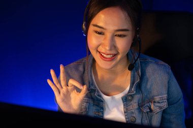 Sunucu kanalı Asyalı etkileyicisi canlı yayında konuşuyor. Sosyal medyada kulaklık takıyor, bilgisayar kaydı yapıyor, dinleyicileri selamlıyor ve Neon Modern Stüdyoları 'nda online olarak koçluk yapıyor. Taktik.