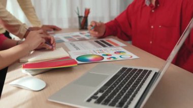 Dizüstü bilgisayarla çalışan grafik tasarım için beyin fırtınası yapan ve renk seçimi yapan tasarımcı takımının yavaş çekim çekimleri. Bu sırada müşteri de ofiste kromatik danışma sırasında projeyi denetliyor. Değiştirilmiş